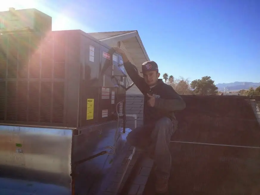 HVAC technician performing Boiler Repair on a rooftop unit in Henniker